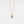 Gold necklace with a purple gemstone on a light gray background
