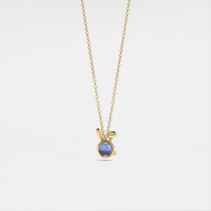 Gold necklace with a purple gemstone on a light gray background