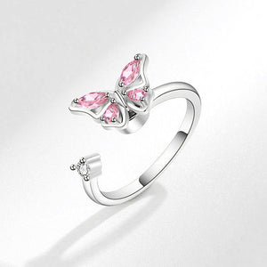 Butterfly-shaped ring with pink gemstones on a light gray background