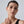 Woman wearing long earrings with a neutral background