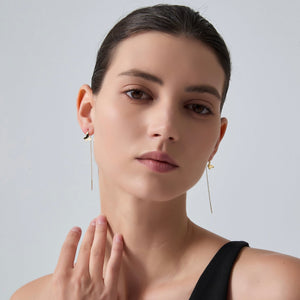 Woman wearing long earrings with a neutral background