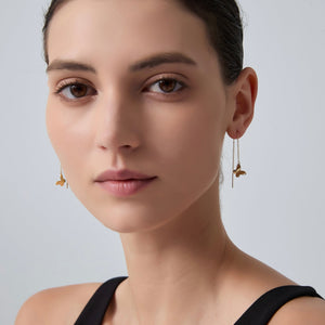 Close-up of a woman wearing gold earrings against a plain background