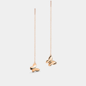 Rose gold butterfly earrings on thin chains against a light gray background