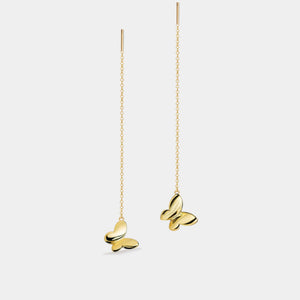 Gold butterfly earrings on thin chains against a light gray background