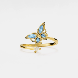 Gold butterfly ring with blue gemstones on a white background