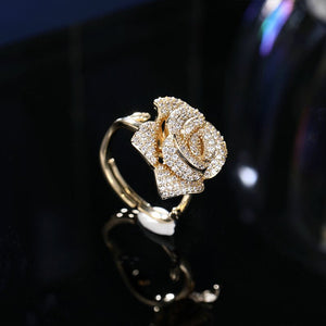 Gold rose-shaped ring on a reflective black surface