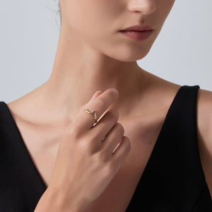 Close-up of a person wearing a gold ring on a plain background