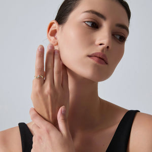 Woman wearing a gold ring on her finger against a plain background