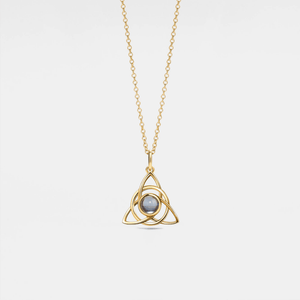 Gold necklace with a triangular pendant on a light gray background