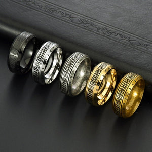 Five rings in black, silver, and gold on a dark surface
