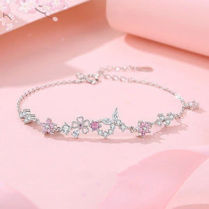 Silver necklace with floral and heart designs on a pink background