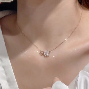 Necklace with a floral pendant on a person wearing a white shirt.