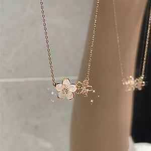 A gold-plated necklace with a cherry blossom charm and a small bee charm on a mannequin.