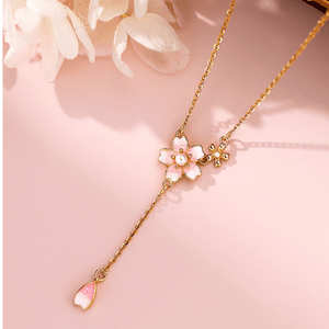 Gold necklace with pink floral pendant on a soft pink background