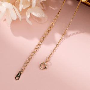 Gold chain necklace on a pink background with floral elements