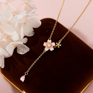 Gold necklace with a pink flower pendant on a pink background