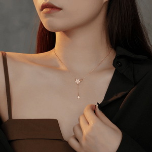 Close-up of a woman wearing a delicate gold necklace with a flower pendant.