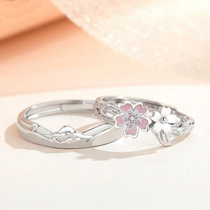 Silver ring with pink flower and white butterfly design on a light background