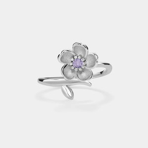A sterling silver ring with a bypass design featuring a floral motif and pink cubic zirconia in the center, on a white background.