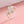 An image featuring two sterling silver rings with cherry blossom flower designs, one open band and one bypass ring, displayed on a pink background.