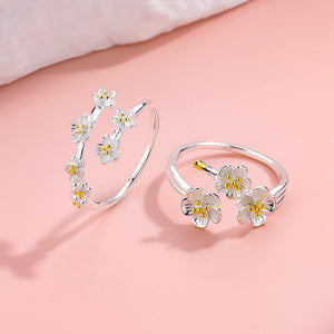 Silver floral bracelet and ring set on a pink background