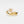 Gold ring with floral design and small diamonds on a white background