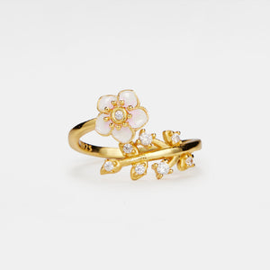 Gold ring with floral design and small diamonds on a white background