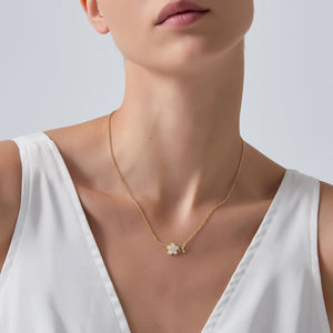 Necklace with a floral pendant worn by a model against a neutral background