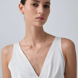Woman wearing a gold necklace against a plain background