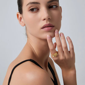 Woman wearing a gold ring on her finger against a plain background