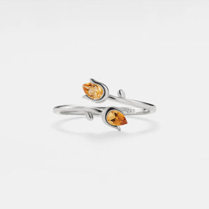 Silver ring with two orange gemstones on a white background