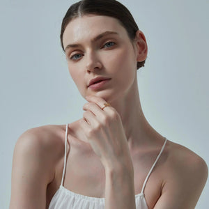 Woman wearing a white strappy top against a light background