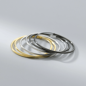 Set of gold silver and black hoop earrings on a gray background
