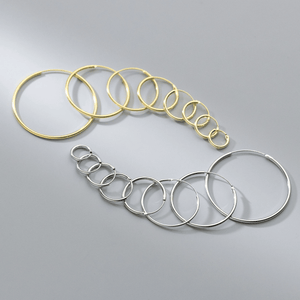 Set of gold and silver hoop earrings on a gray background
