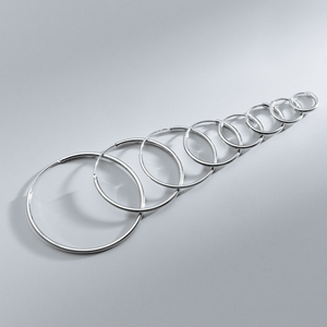Set of silver hoop earrings on a gray background