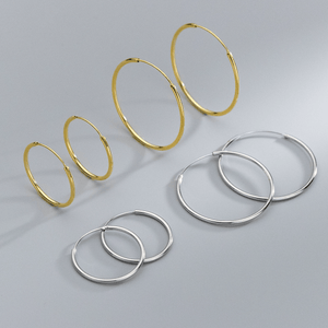 Set of gold and silver hoop earrings on a gray background