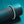 Silver bracelet on a black cylindrical stand against a teal background
