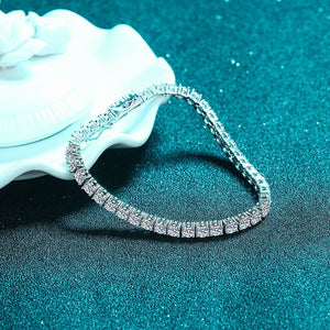 Silver bracelet with clear stones on a textured teal surface