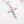 Cross-shaped pendant with colorful gemstones on a white background