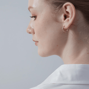 A model wearing gold-plated twisted rope hoop earrings on a white background