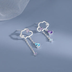 Silver cloud-shaped earrings with gemstone drops on a light blue background