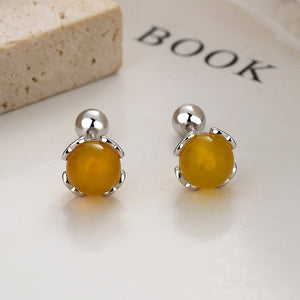 Yellow stud earrings with silver posts on a white surface.