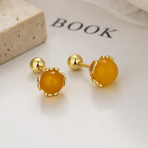 Gold earrings with yellow gemstones on a light surface