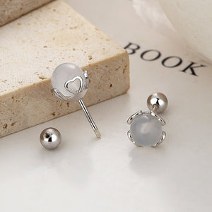 Silver earrings with heart design on a white surface