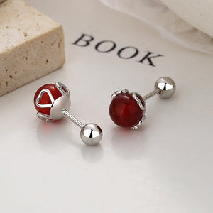 Pair of red gemstone earrings with silver posts on a white surface.