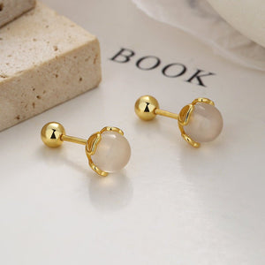 Gold earrings with clear stones on a white surface with 'BOOK' text.