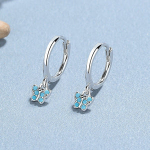 A collection of hoop earrings with butterfly charms attached, displayed against a blue background.