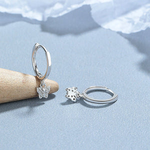 A collection of hoop earrings with butterfly charms attached, displayed against a blue background.