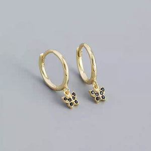 A collection of hoop earrings with butterfly charms attached, displayed against a blue background.