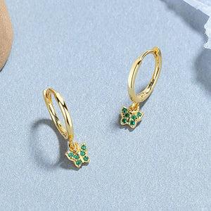 A collection of hoop earrings with butterfly charms attached, displayed against a blue background.
